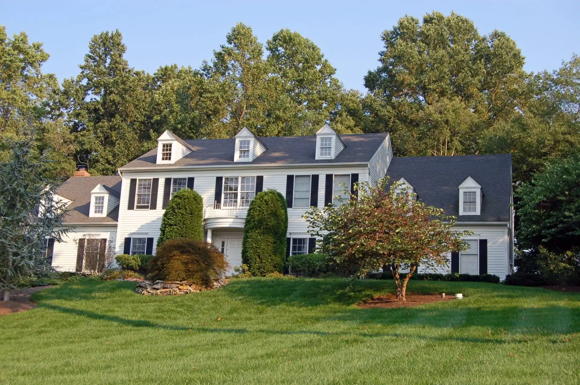 Colonial home with dormers and lawn